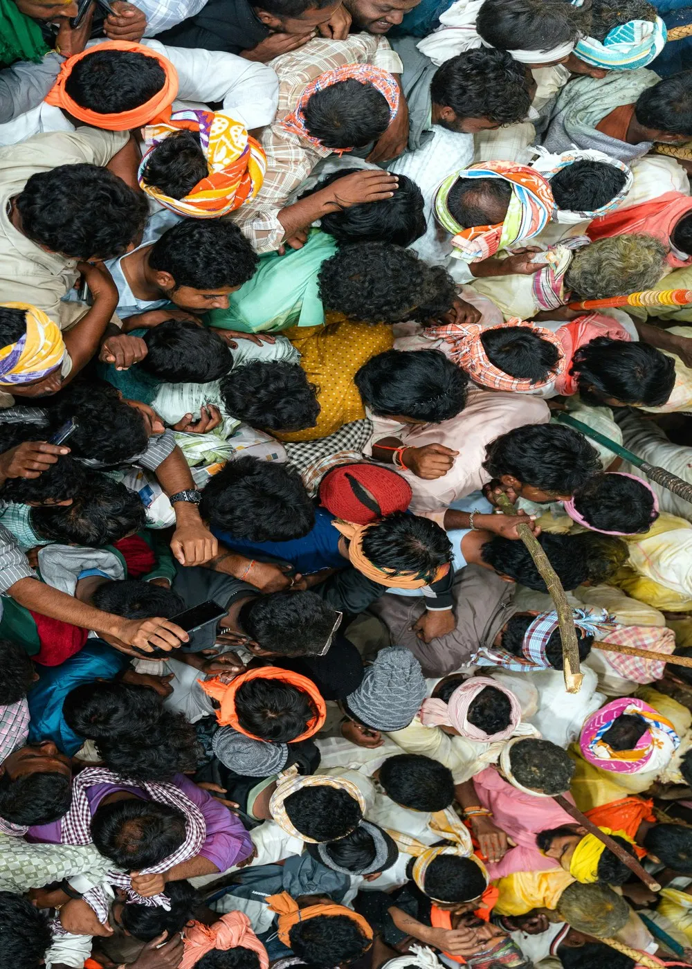 Dozens of people photographed from directly overhead, scattered across an open ground.