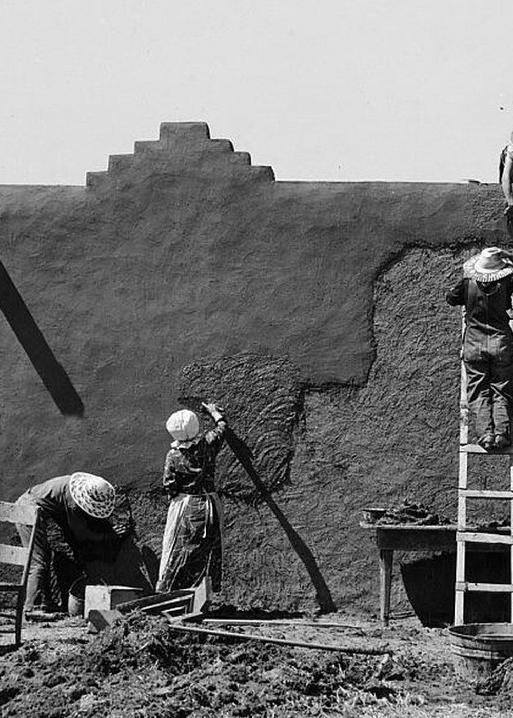 Women replastering an adobe wall together.